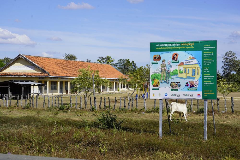 A billboard displaying phone numbers and helplines for the relevant local authorities and police to help combat child abuse in rural Cambodia.