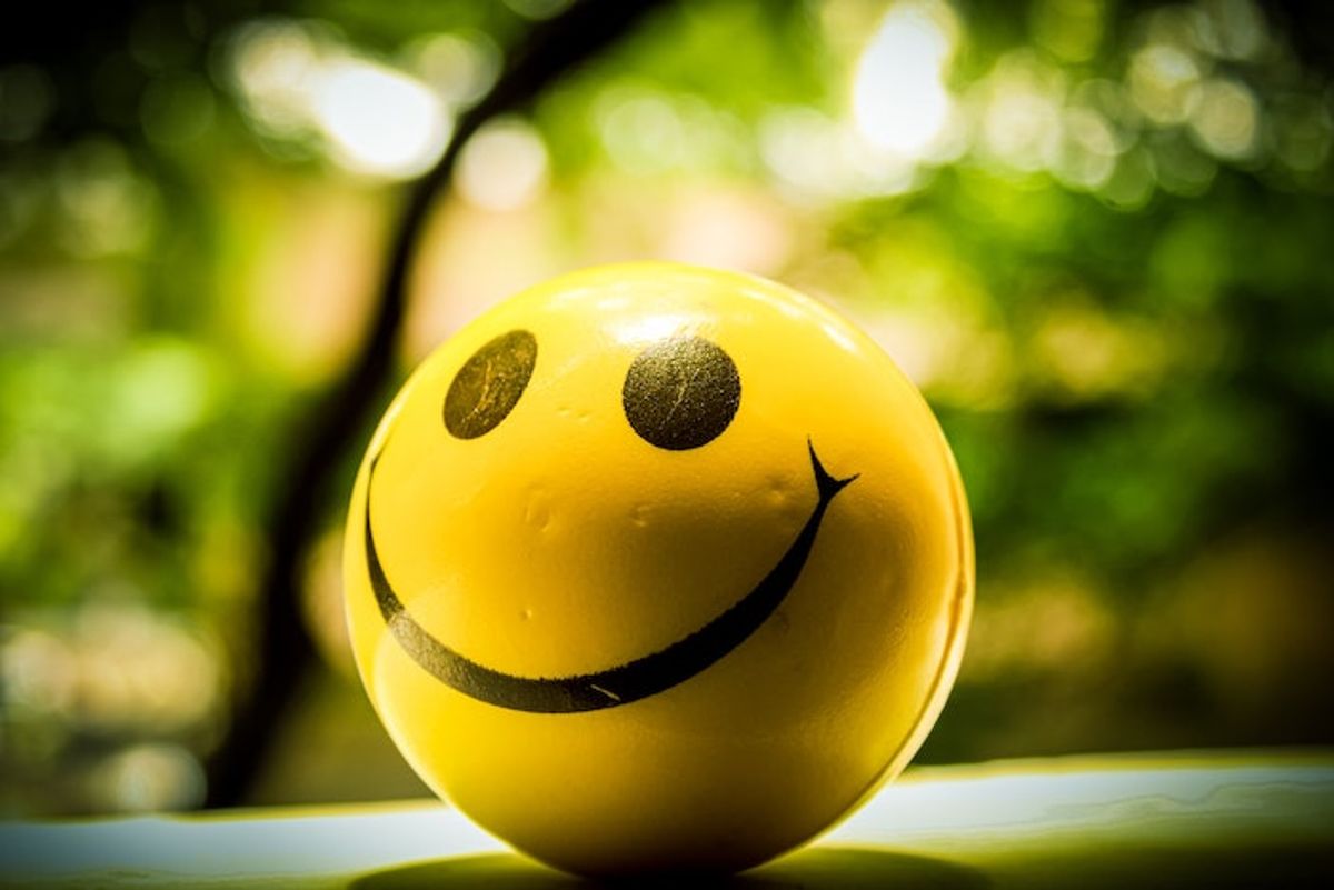 Smiley face ball against a leafy background. Photo by chaitanya pillala on Unsplash.