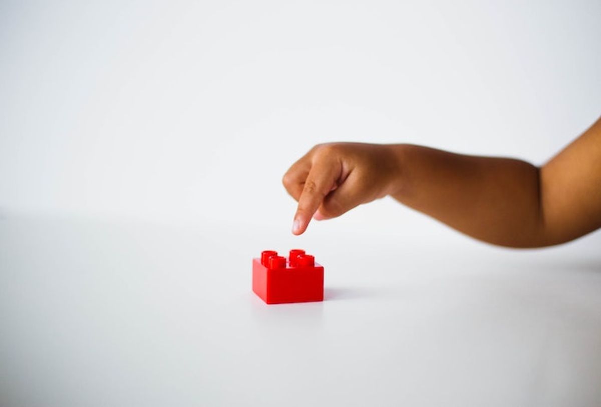 Child with one red lego block. Playing with Lego has revealed a new cognitive bias. Photo by @calebeangel via Unsplash.