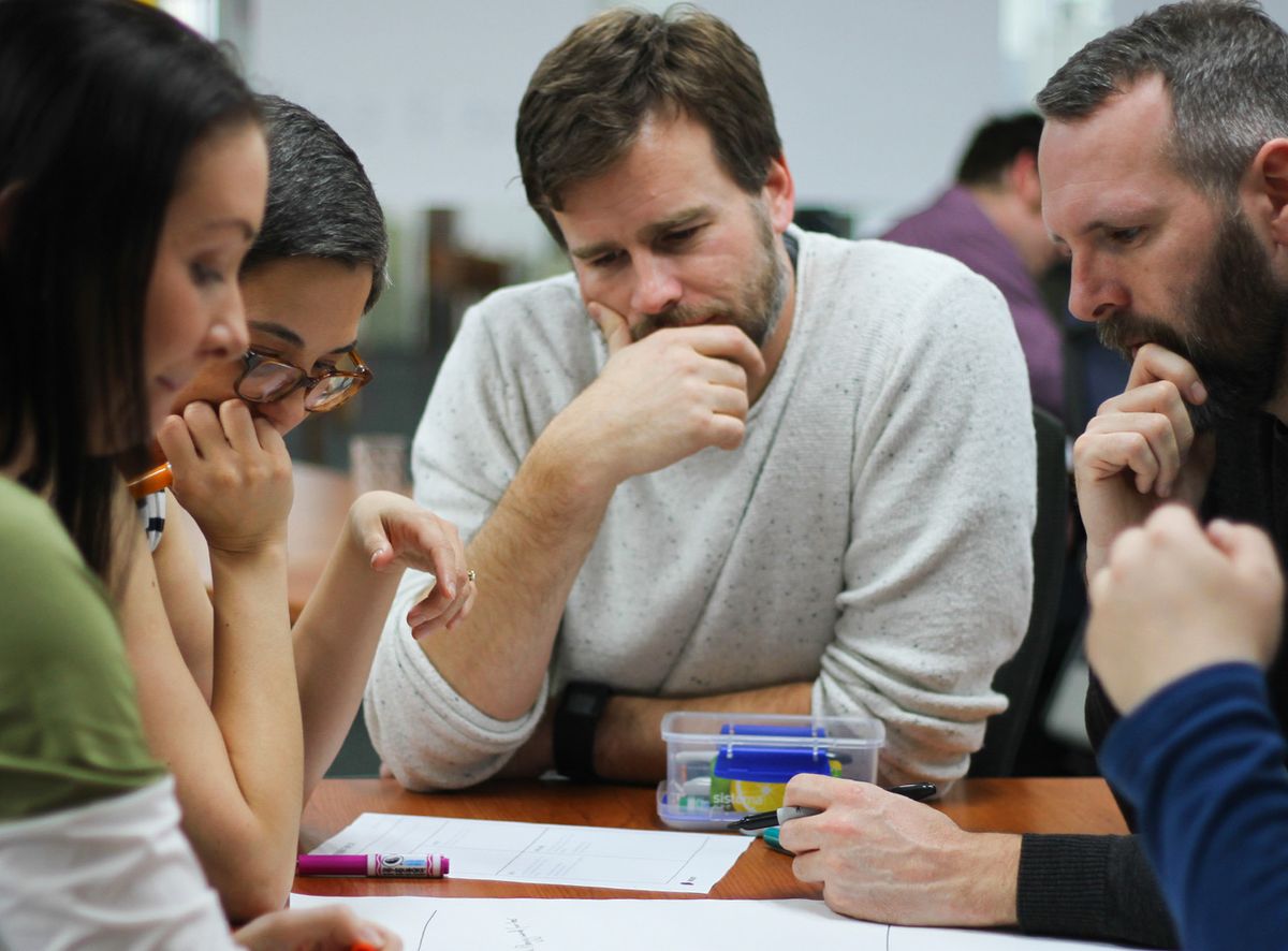 A Scrum team working together around a table. A successful Scrum team leverages the Scrum roles and processes in order to deliver maximum value.