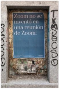 Affiche bleue collée dans une porte cochère taguée, proclamant en espagnol que Zoom n'a pas été inventé pendant une réunion Zoom.