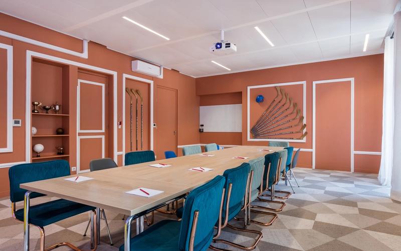 Sala de consejo de Comet Étoile: gran mesa de madera, sillones azul petróleo y paredes de terracota.