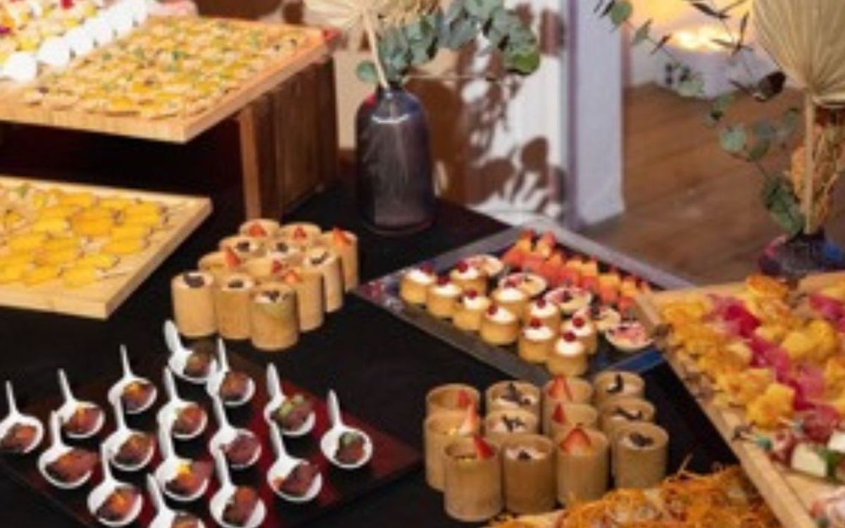 A catering buffet of savoury and sweet bites arranged on wooden and slate trays, decorated with dried flowers and eucalyptus.
