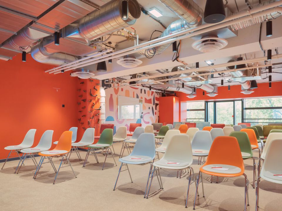A bright, contemporary conference room at Comet Bercy, set up in a plenary configuration with colorful seating. Its bold design, open layout, and dynamic atmosphere make it an ideal setting for hosting conferences, presentations, seminars, and key collective events in a stimulating and welcoming environment.