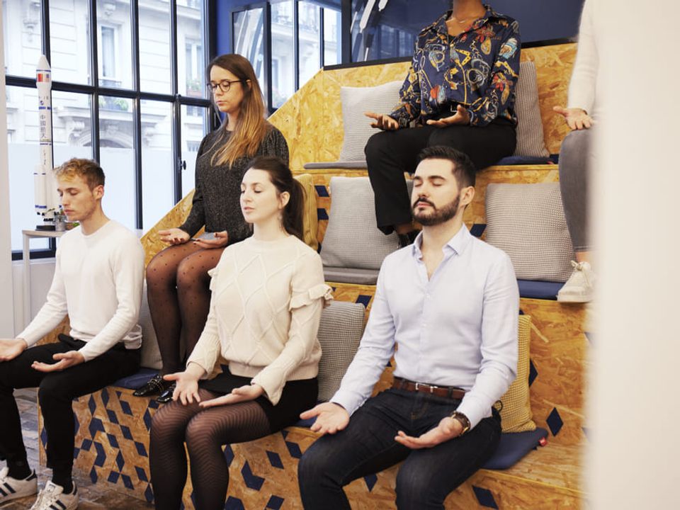 A wellness session organized in a Comet space, where several participants take a break to pause and refocus in a calm and soothing atmosphere. The image highlights a well-being experience integrated into the event, designed to promote relaxation, concentration, and balance throughout the day.