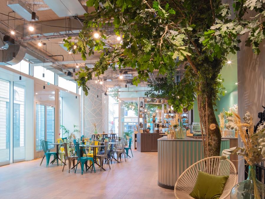 Un grand arbre et des guirlandes lumineuses au-dessus des tables colorées du bar de Comet Bourse