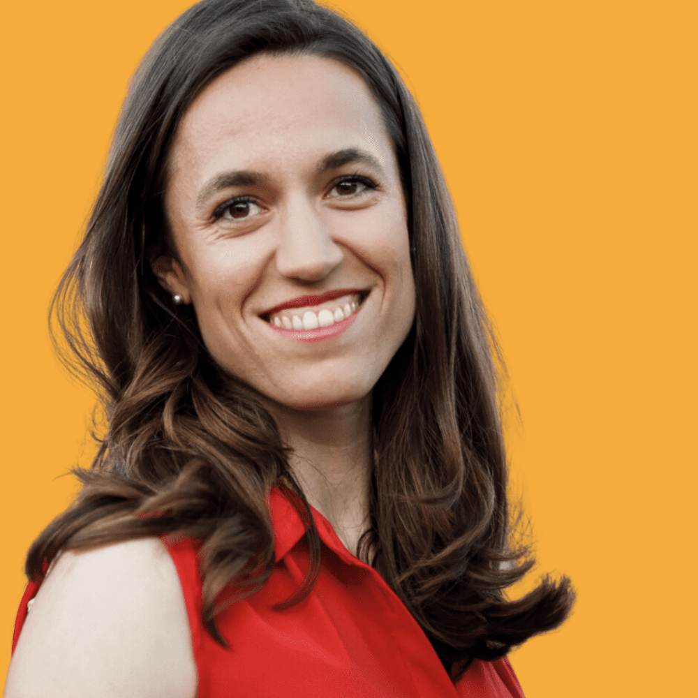 Romina Maillochaud, glimlachend, met lang bruin haar en een rode mouwloze blouse, tegen een gele achtergrond.