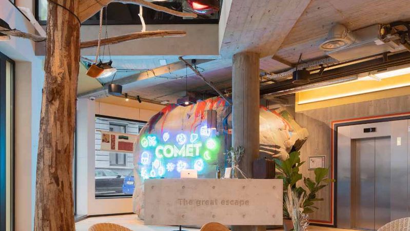 Een onthaalhal met een boomstam, een neonbord van Comet op een rotsachtig decor en een betonnen balie met het opschrift "The great escape".