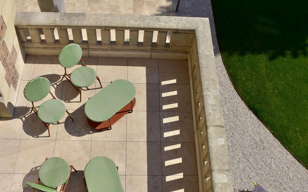 Overhead view of the terrace at Le Grand Comet and its green garden furniture