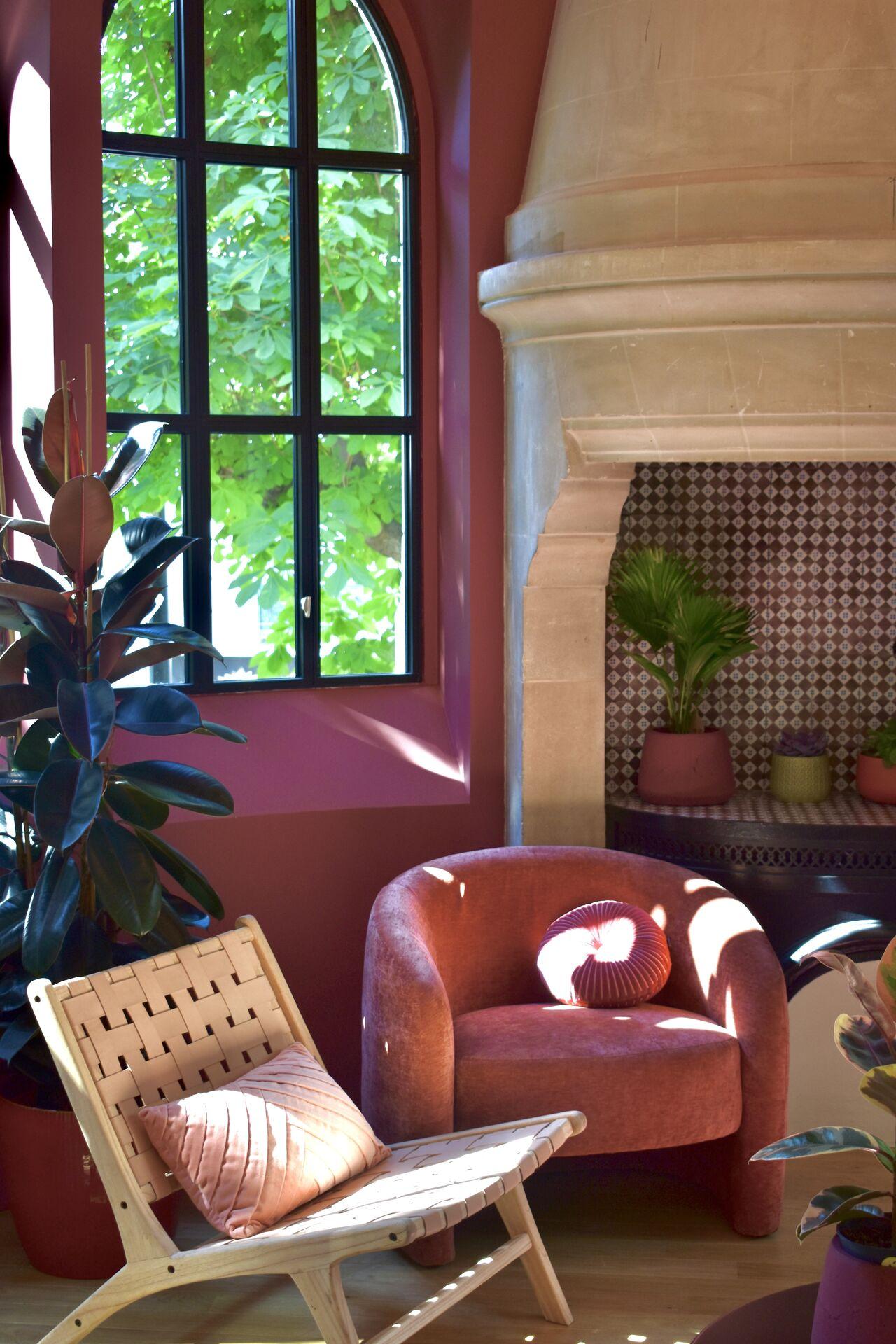 Lounge at Le Grand Comet with a stone fireplace, cognac leather armchair and a tall window onto the grounds