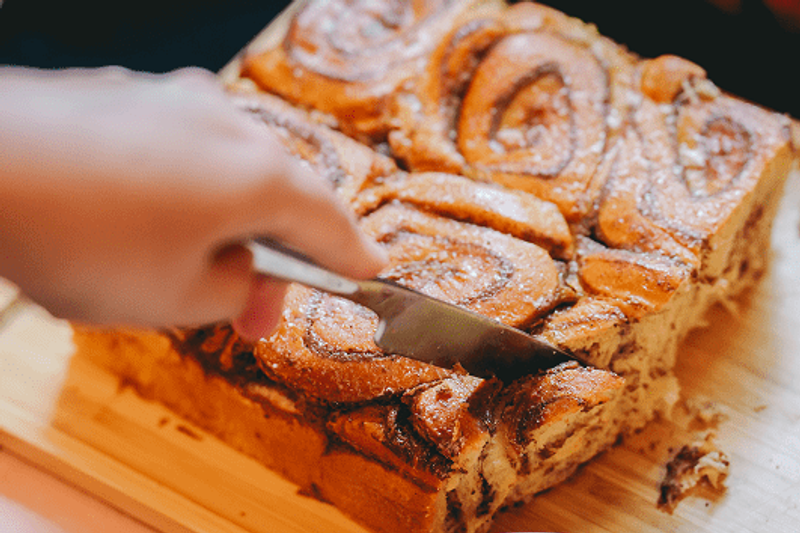 Une scène gourmande et spontanée autour d’un dessert généreux, découpé juste avant d’être partagé. La lumière douce, les textures dorées et la mise en scène naturelle évoquent une cuisine conviviale, sincère et réconfortante, pensée pour accompagner les moments d’échange.