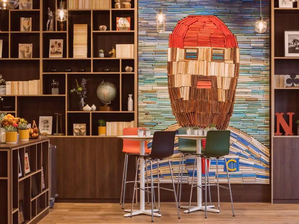 A warm and creative space at Comet Étoile, defined by unique decor, a wall-mounted library, and an artistic mural made from books. The image highlights an inspiring seminar venue where design, friendliness, and a homely atmosphere come together to offer teams a setting that is professional, original, and memorable all at once.