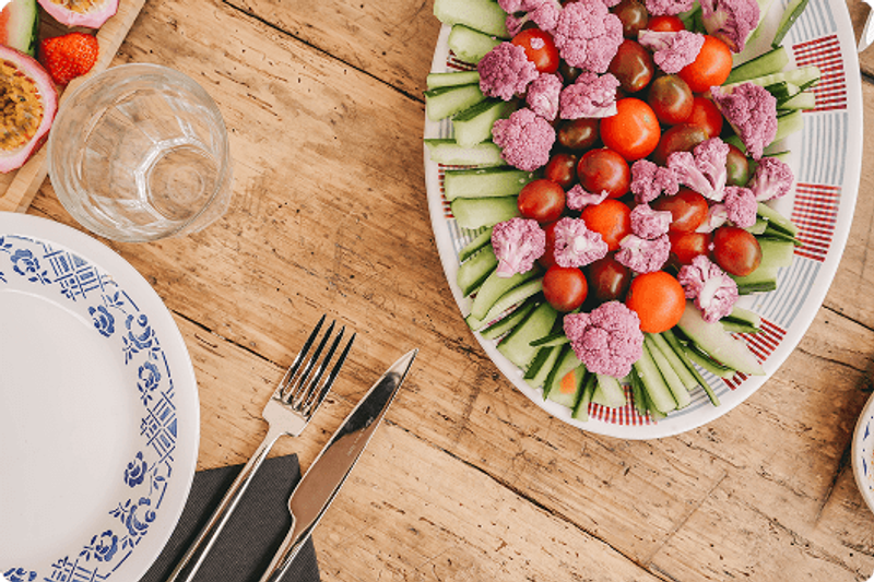 Une mise en scène gourmande et colorée autour d’une table conviviale. Les légumes frais, joliment disposés, évoquent une cuisine saine, généreuse et de saison, pensée pour accompagner les moments de partage dans une atmosphère chaleureuse et décontractée.