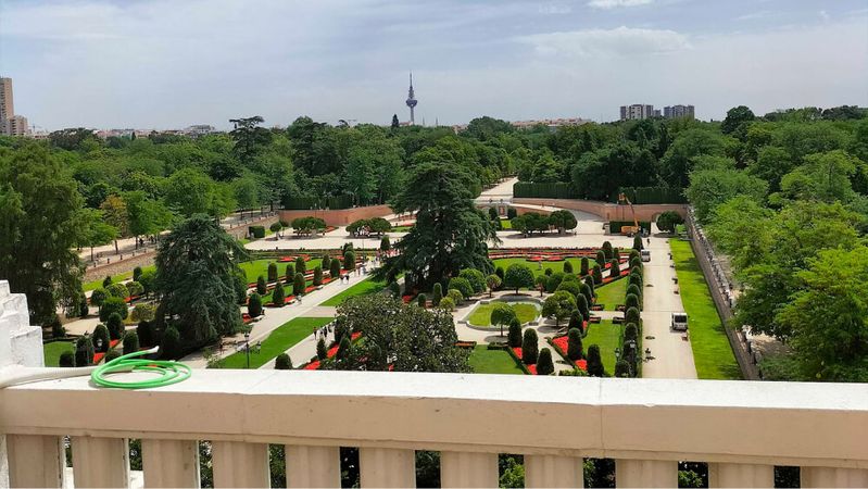 A view from a balustraded terrace over the clipped gardens of Retiro Park and, further off, the rooftops of Madrid.