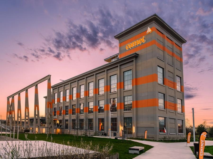 La façade industrielle de Comet Arboretum illuminée au coucher du soleil, ciel rose au-dessus des pelouses