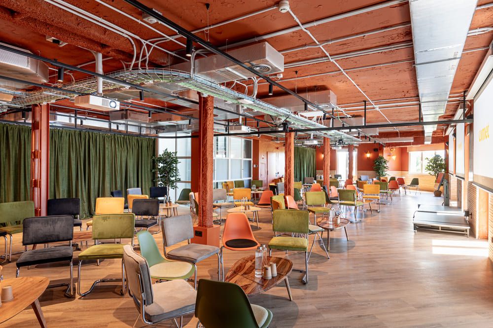 Una planta en configuración cabaré, con cortinas de terciopelo verde, pilares naranjas y un pequeño escenario al fondo.