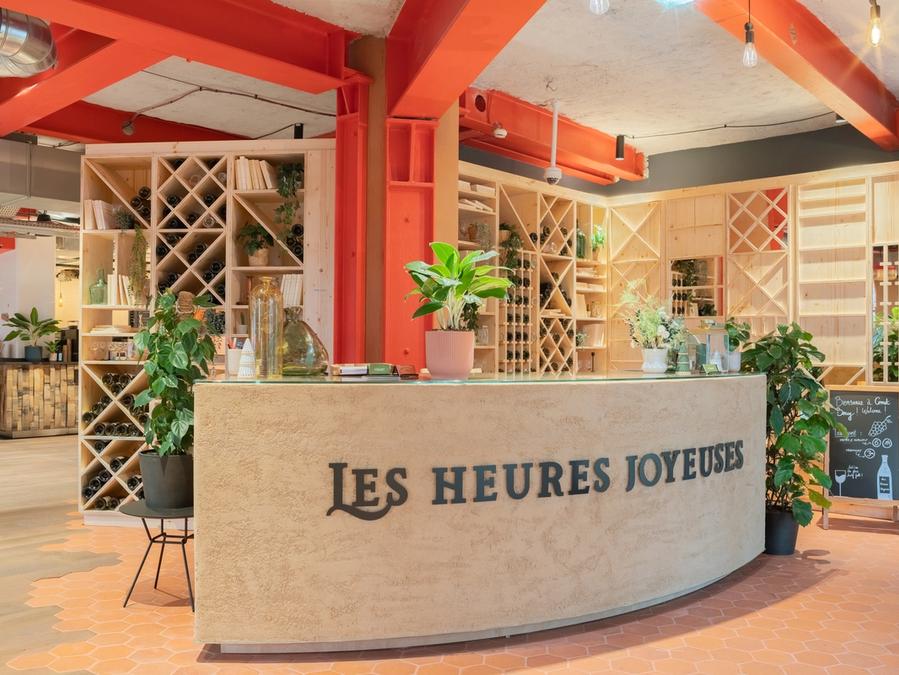 Le bar les heures joyeuses de Comet Bercy, son comptoir arrondi, ses casiers en bois clair et ses plantes vertes