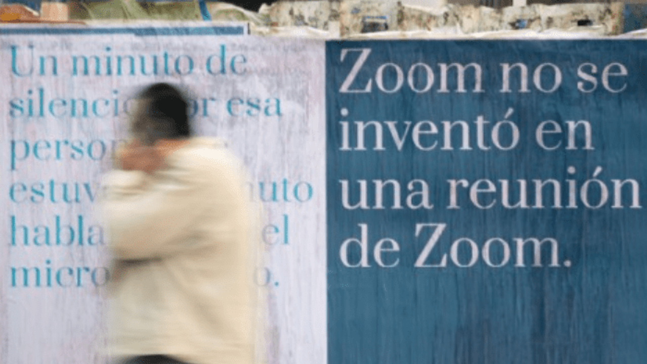 Twee campagneaffiches op een Madrileense schutting, met een wazige voorbijganger ervoor.