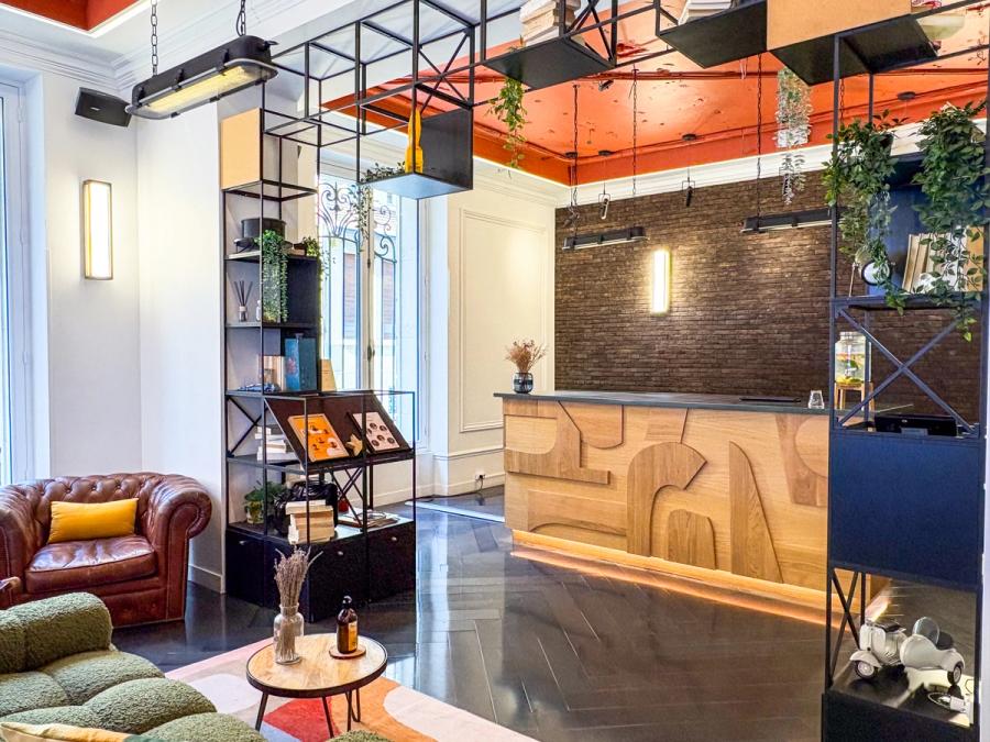 Le lobby de Comet Étoile avec sa banquette verte, son canapé en cuir et son comptoir d'accueil en bois sculpté