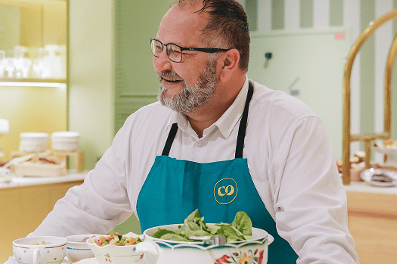 Le chef Vakhtang Meliava au cœur de l’expérience culinaire Comet : une présence chaleureuse, un service attentif et une cuisine pensée pour créer du lien. L’image met en avant l’humain derrière le buffet, dans une ambiance conviviale, élégante et naturellement accueillante.