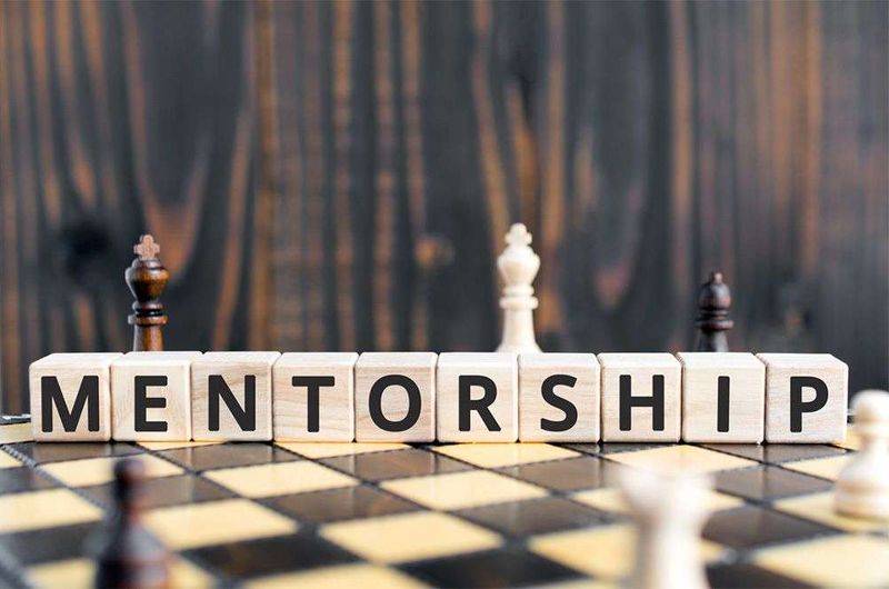 Mentorship spelled out in blocks over a chess board.