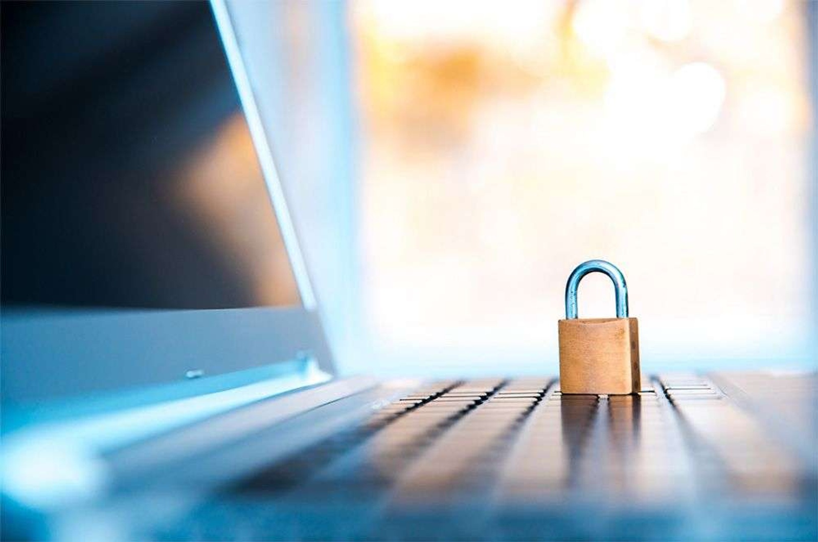 A padlock is positioned on a laptop to symbolize security of contacts.