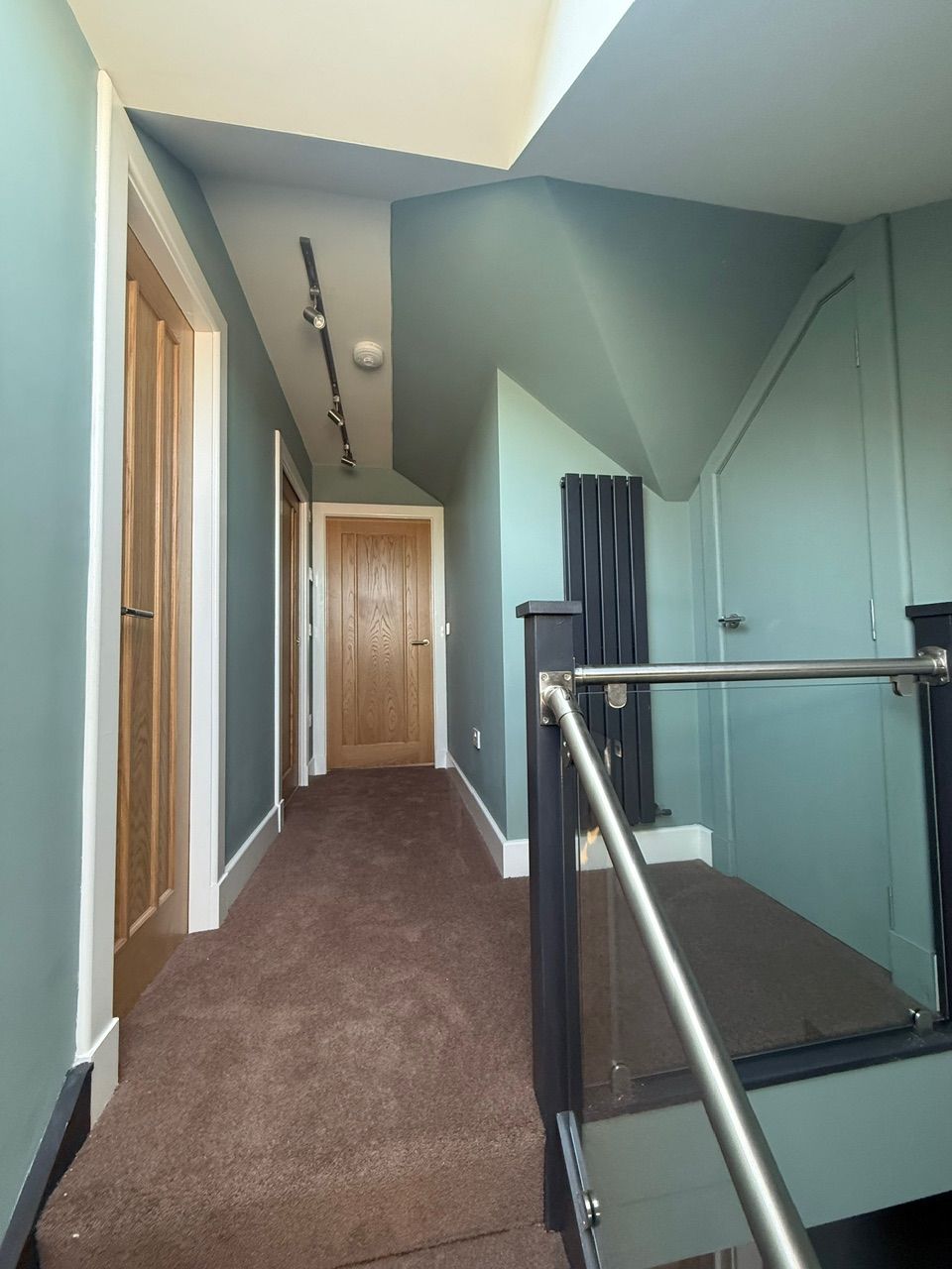Finished loft landing with glass balustrade and timber doors at Fernielaw Avenue