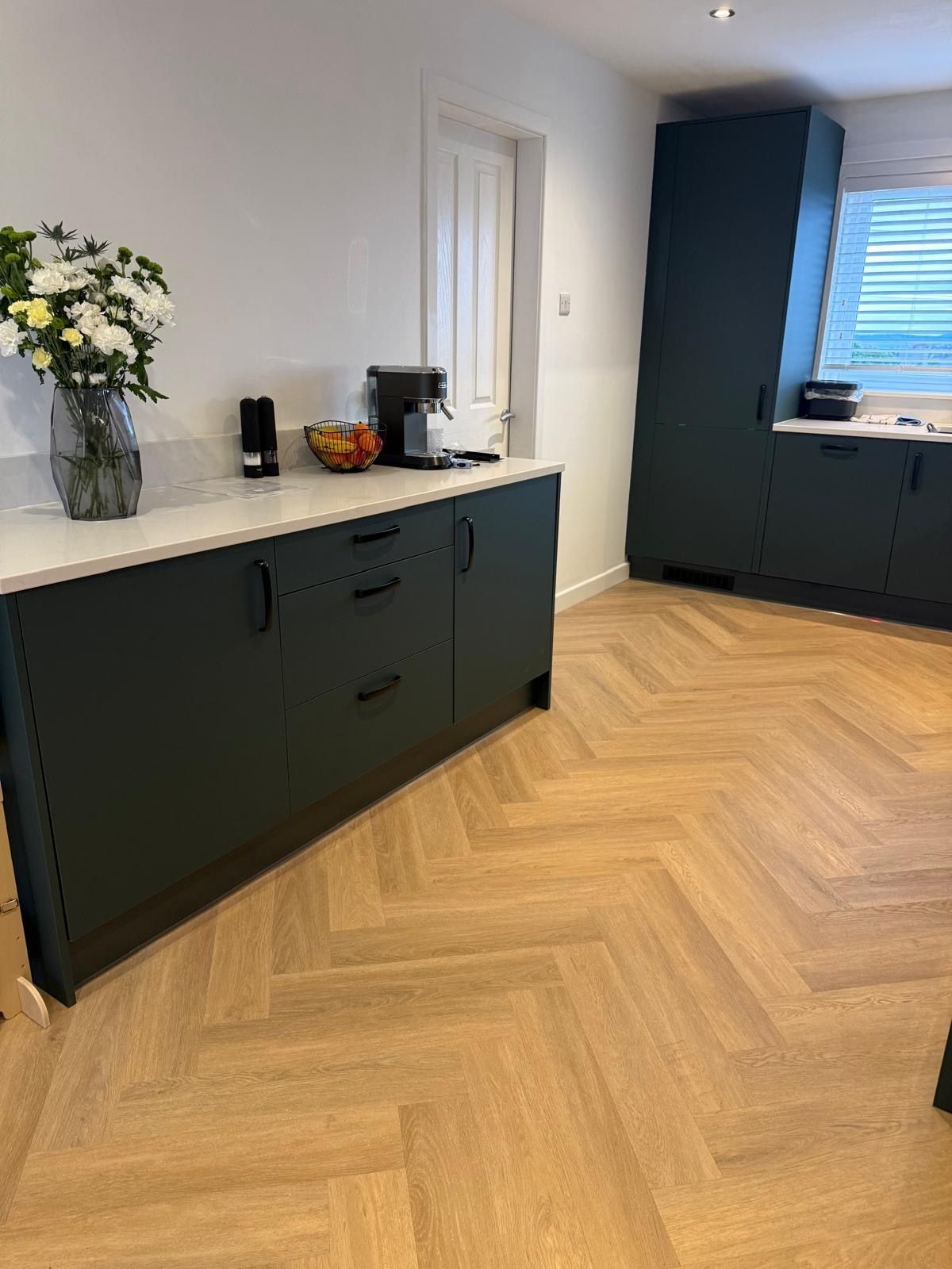 Herringbone vinyl flooring continuing from the kitchen through the downstairs area