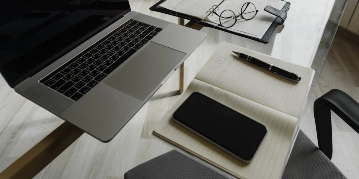 Workspace with laptop, planner and smartphone showing propose new time google calendar for meeting rescheduling