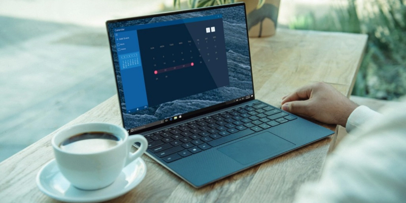 Pessoa olhando para um calendário em um laptop com um software de agendamento que integra com o Outlook, com uma xícara de café sobre a mesa