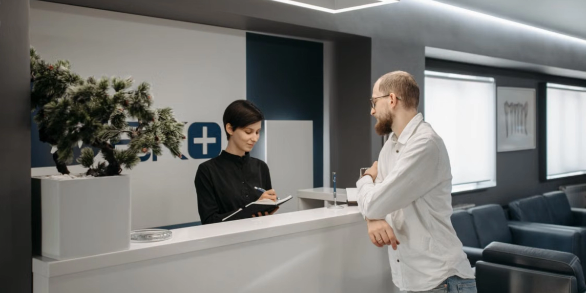 elegant clinic reception with a women wearing dark shirt and a patient during registartion with the best patient scheduling software for clinics