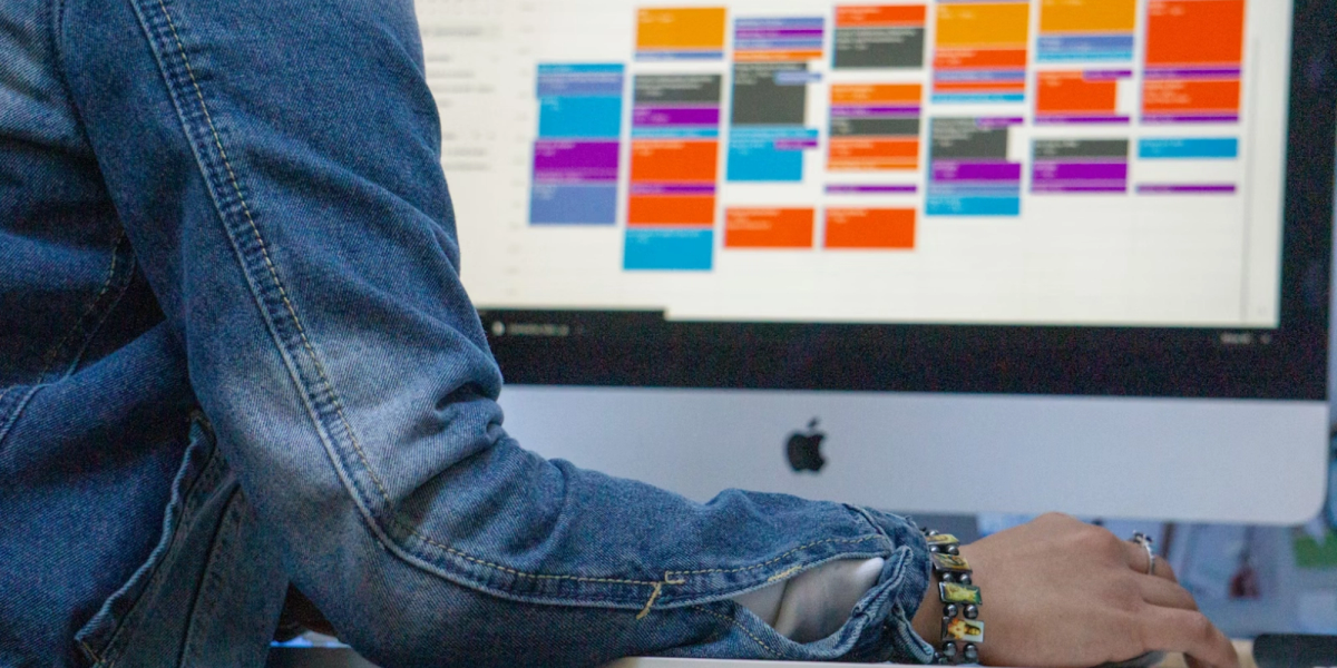Person in front of a Mac computer with a Google Calendar schedule on the screen