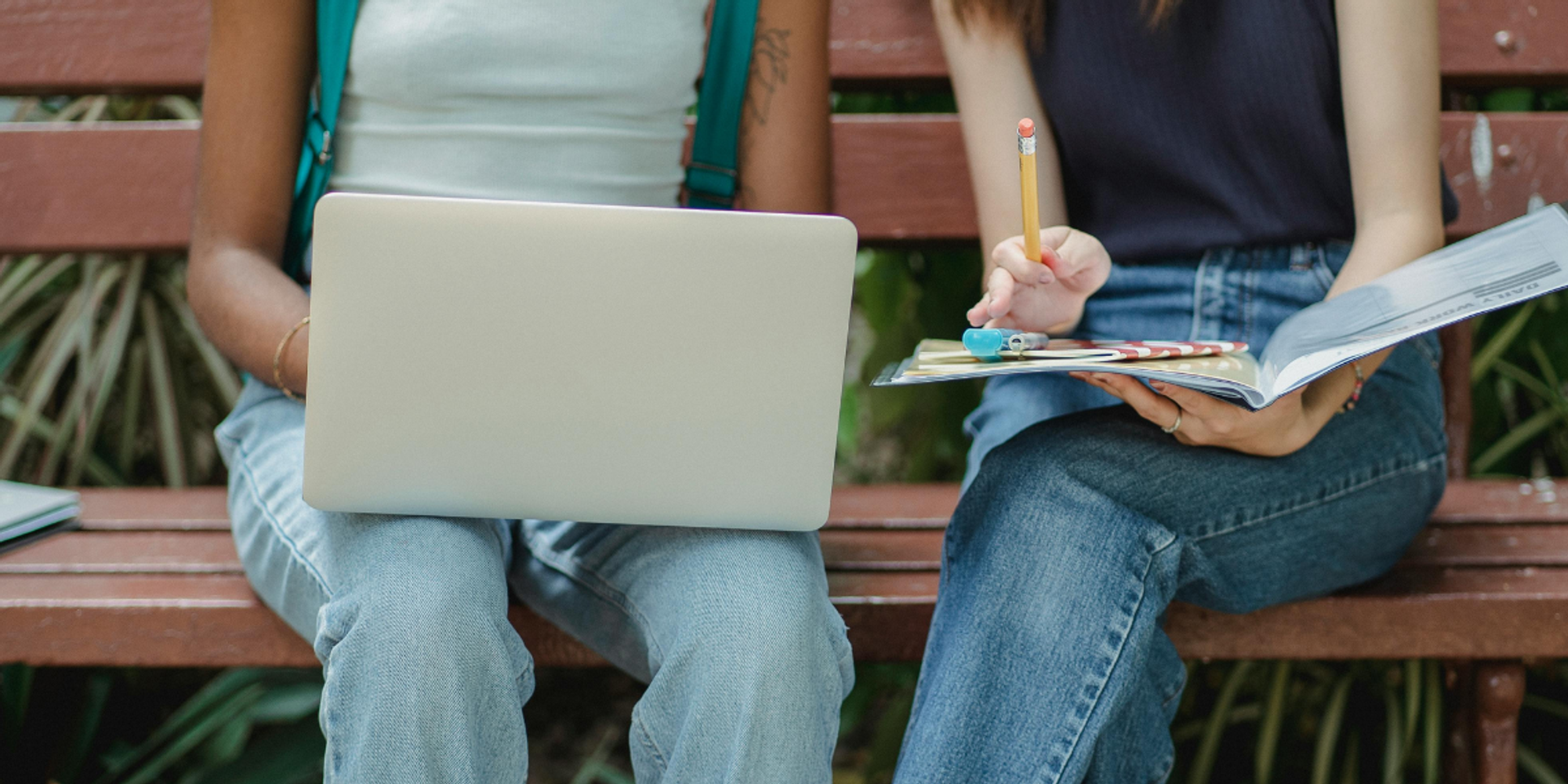 dos estudiantes chicas en un banco utilizando herramientas de colaboración en línea para estudiantes