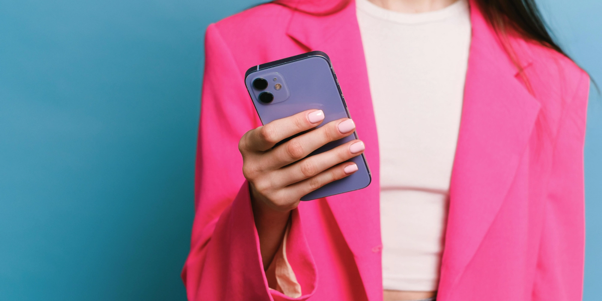 woman in pink jacket checking on her iphone how to use iphone calendar as a planner