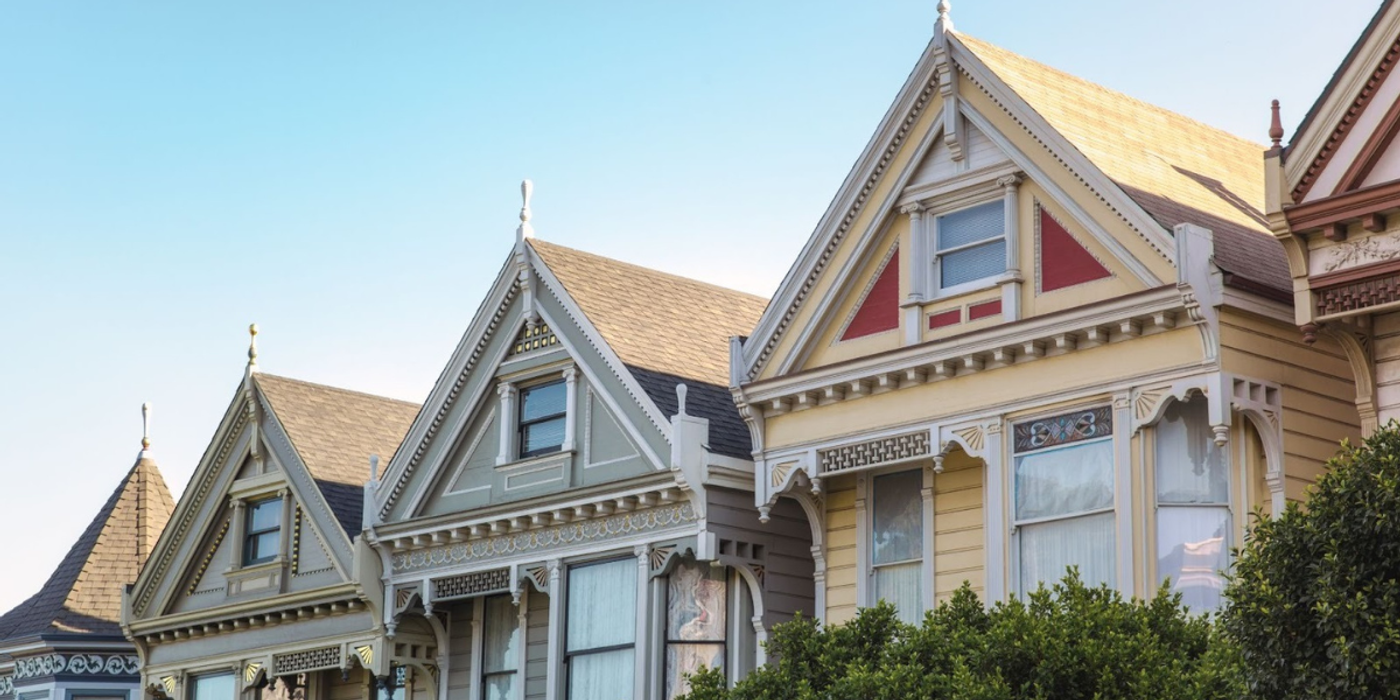 Row of colorful Victorian-style homes with ornate trim under a clear sky