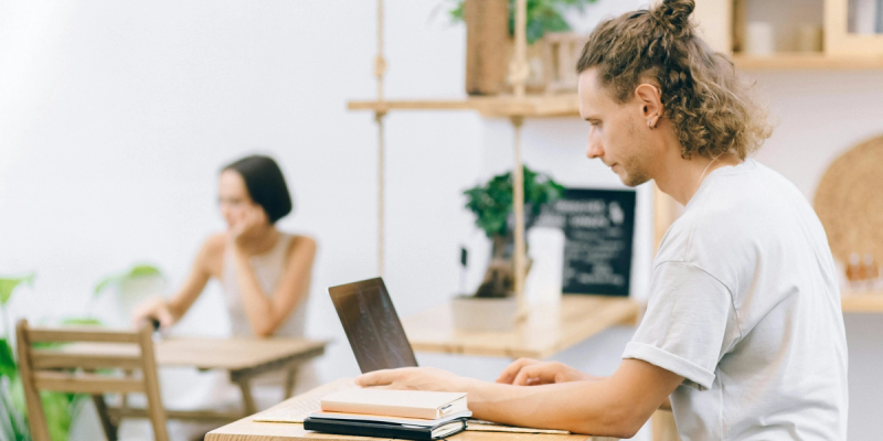 Young man with long hair working on a laptop while researching how to cancel Calendly subscription