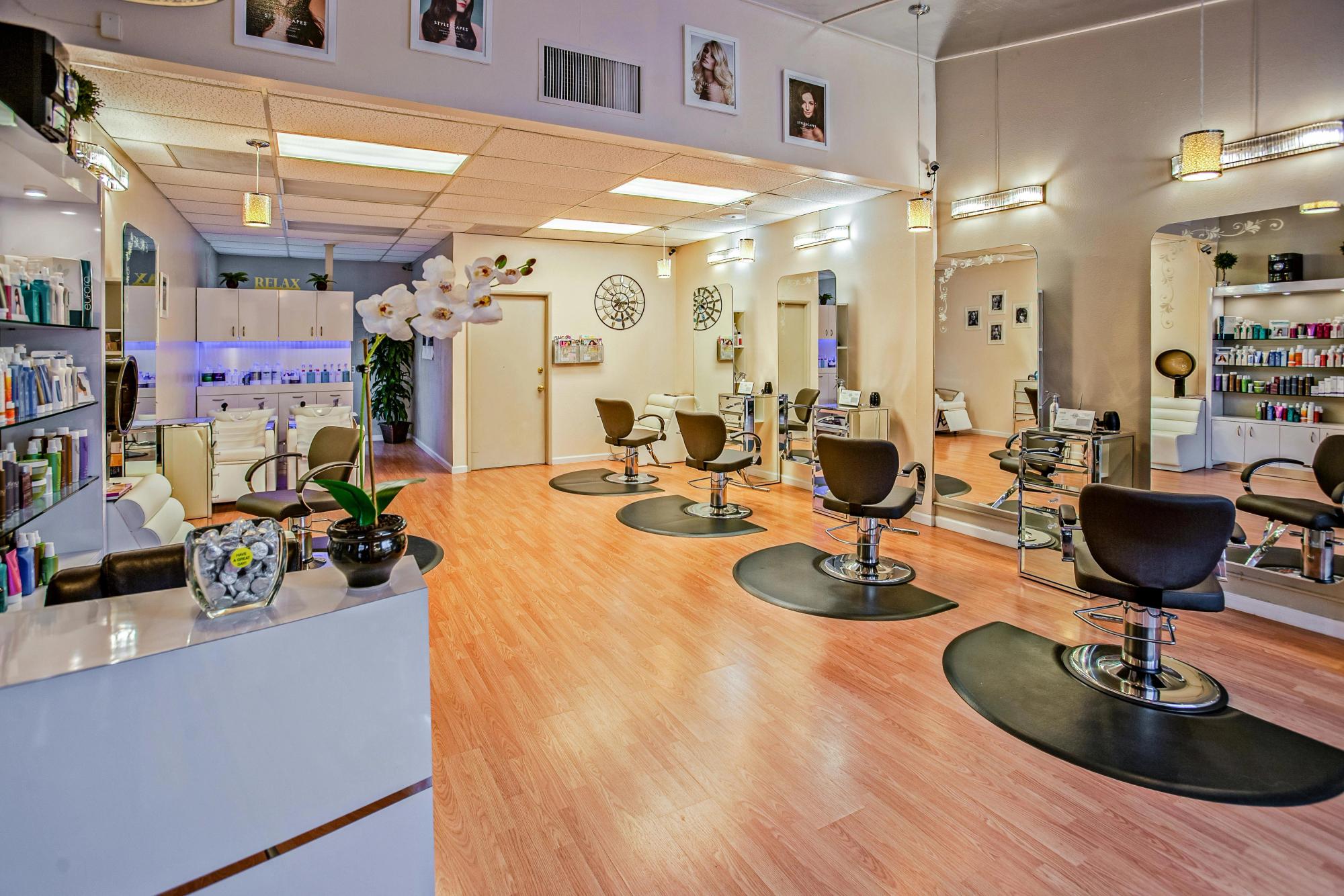 Interior of a nail salon with wooden floors and black seats