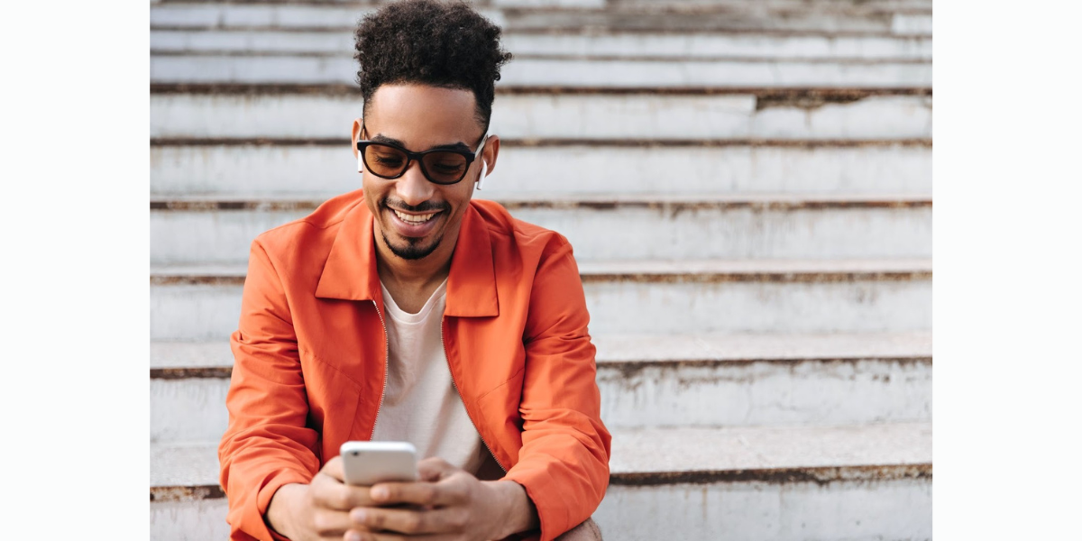 Man in a collared orange shirt with sunglasses replying to a Google Calendar appointment text reminder