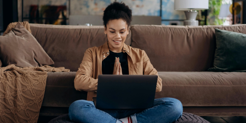 Afro American lady sitting on the floor with computer solving Scheduling conflicts