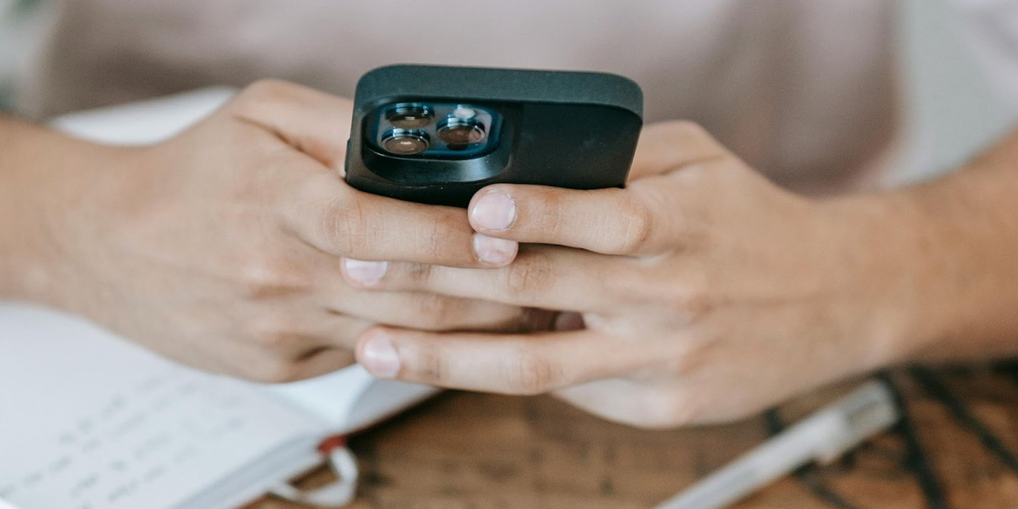 Close-up of someone on their phone at a desk scheduling SMS reminders with Google Calendar