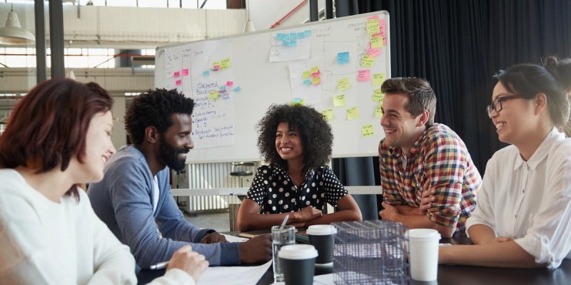 five people by the table smiling and talking during a meeting scheduled with google forms scheduling poll