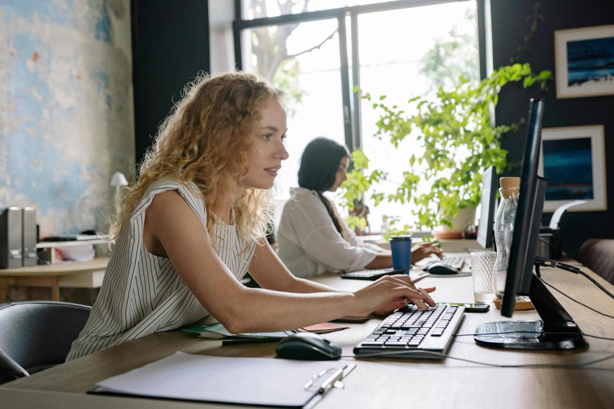 Donne sedute alla scrivania al computer che risolvono conflitti di pianificazione