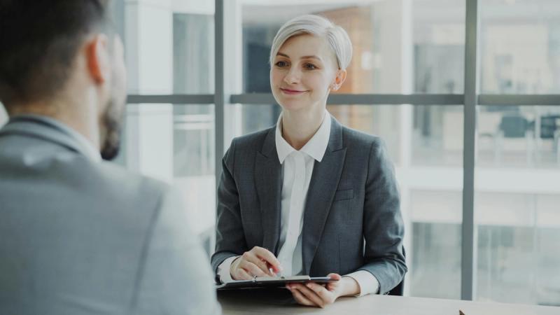 mujer rubia y elegante con traje gris durante una entrevista programada con un software de gestión de entrevistas