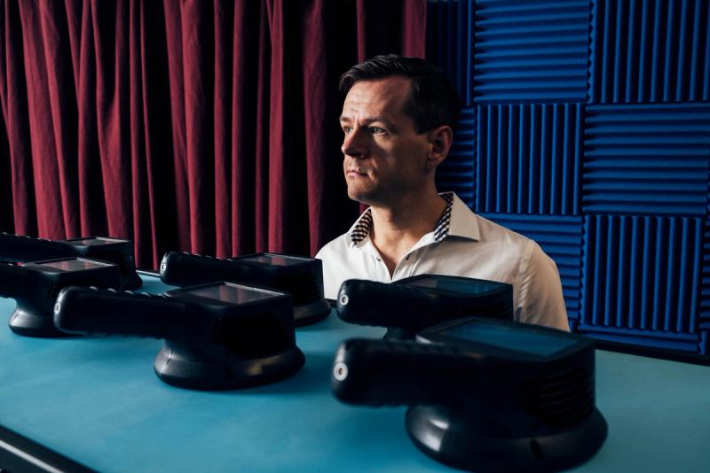 Kai Saksela standing behind a showroom table of NL acoustics camera products