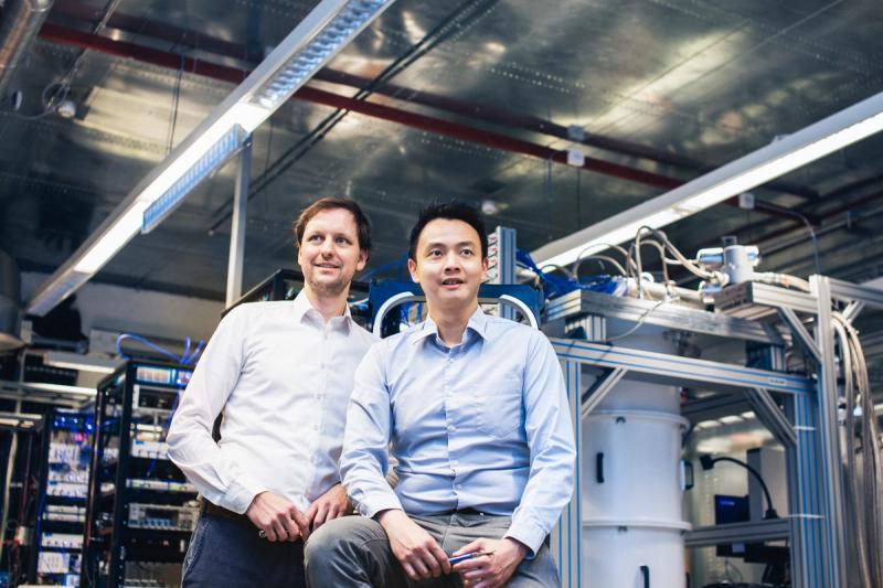 Jan Goetz and Kuan Yen Tan sitting in front of a large quantum computer