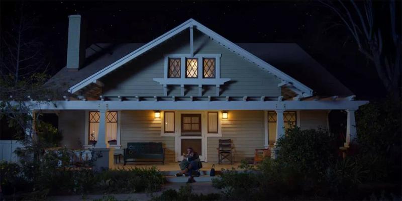 A boy and a man sitting on a front porch of a small town home.