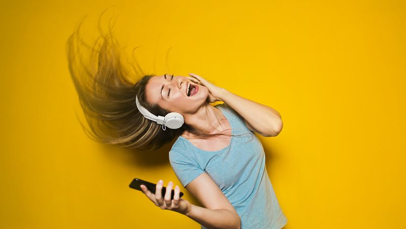 A cheerful woman listening to music on headphones and dancing