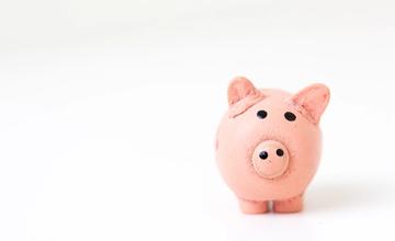 A pink pig ornament, with rough features, and painted eyes and nostrils. With a white background.