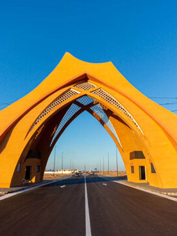 A yellow arched gateway over the road into Laâyoune
