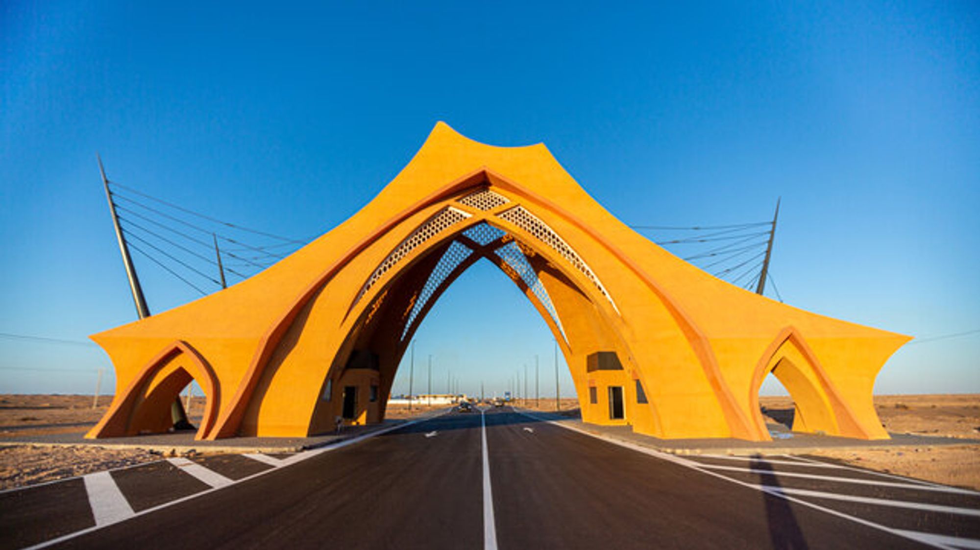 A yellow arched gateway over the road into Laâyoune